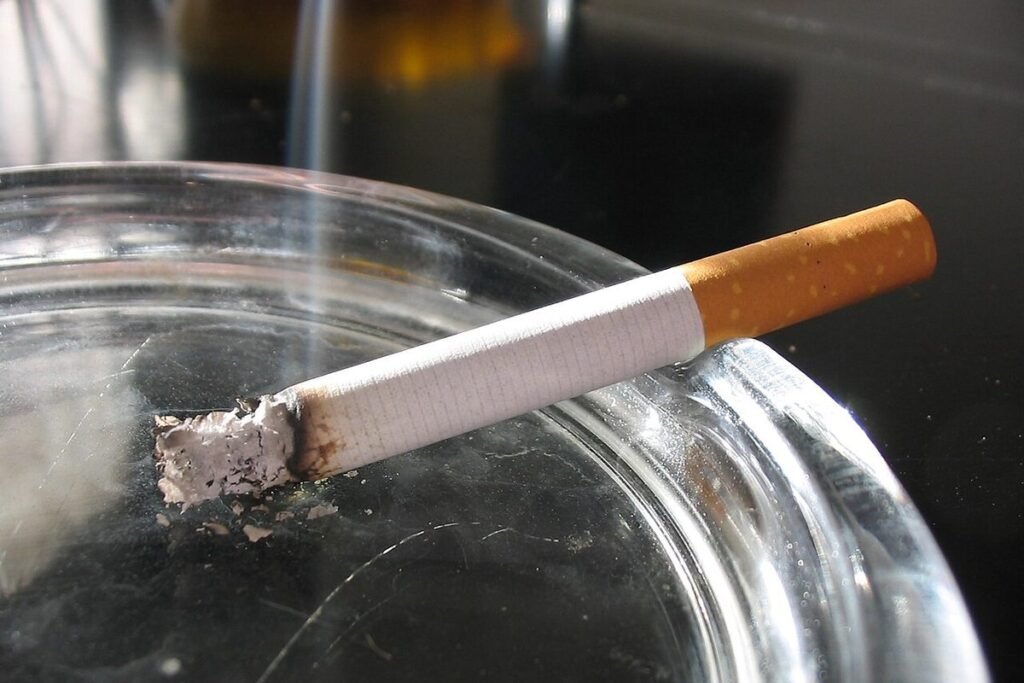 Cigarette posée sur le bord d'un cendrier en verre
